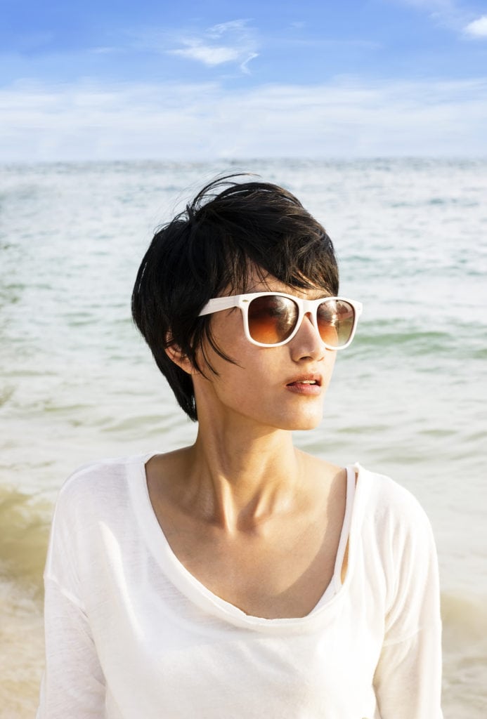 Short hair Asian woman on the beach with sunglasses and short hair cut